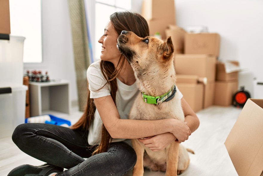 A woman hugs her pet dog in a room.