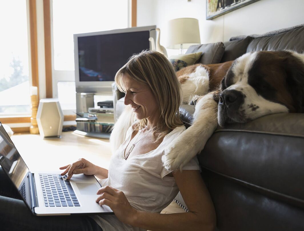 Woman working on laptop with dog