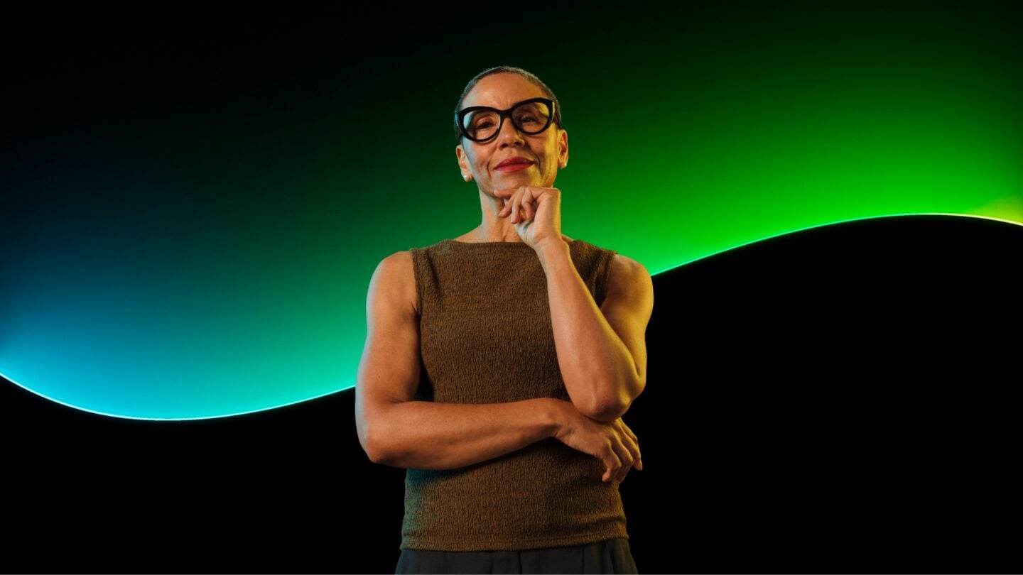 A woman stands in front of the Sage glowline with a black background.