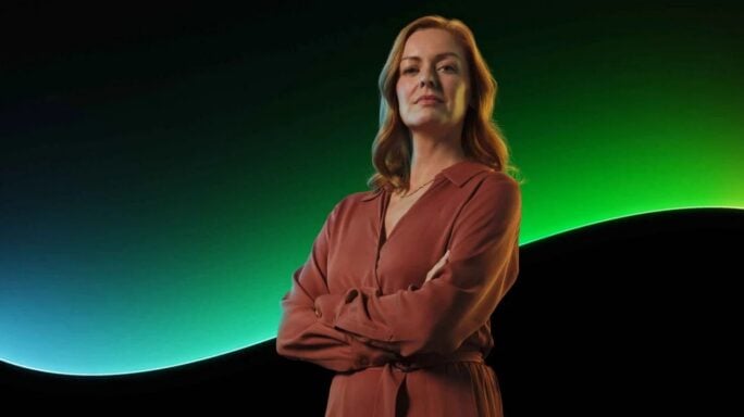 A woman stands in front of the Sage glowline with a black background.