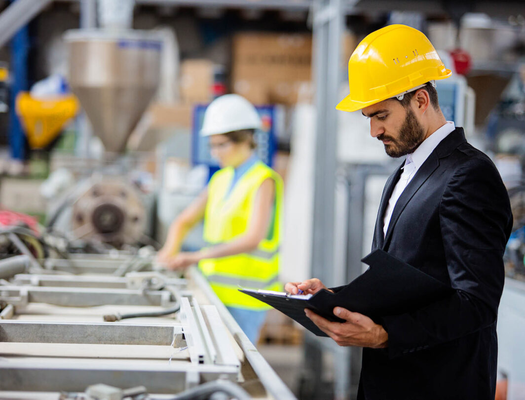 Un homme avec un casque dans une fabrique regarde sa tablette