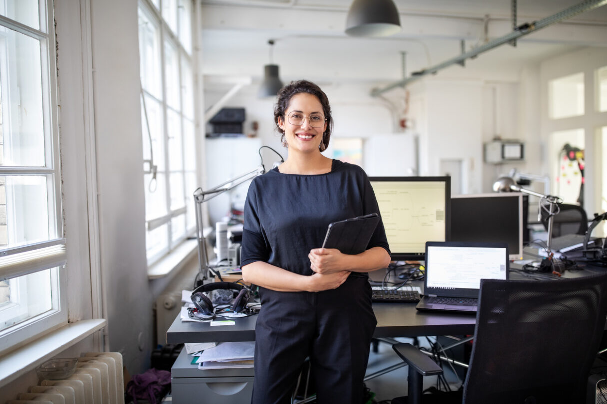 Une femme est dans le bureau, elle est heureuse parce que son entreprise travaille avec un ERP.