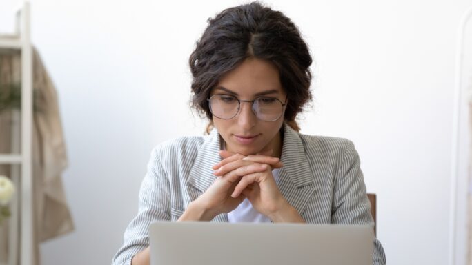 Une femme regarde son ordinateur portable et pense à choisir un expert-comptable pour son entreprise.
