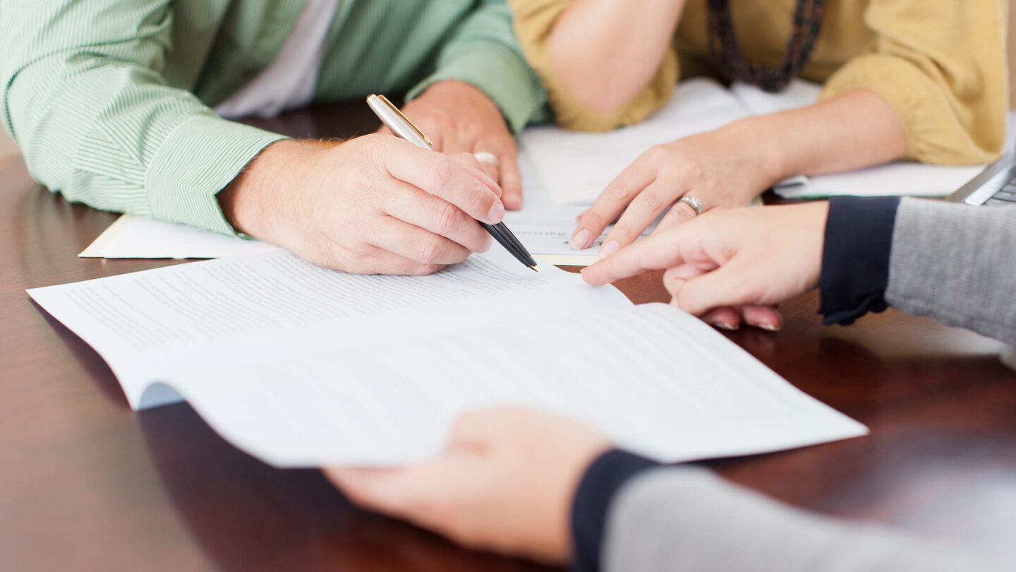 Un homme et une femme signent des documents chez leur expert-comptable, dans le cadre de leur enrôlement de clients.