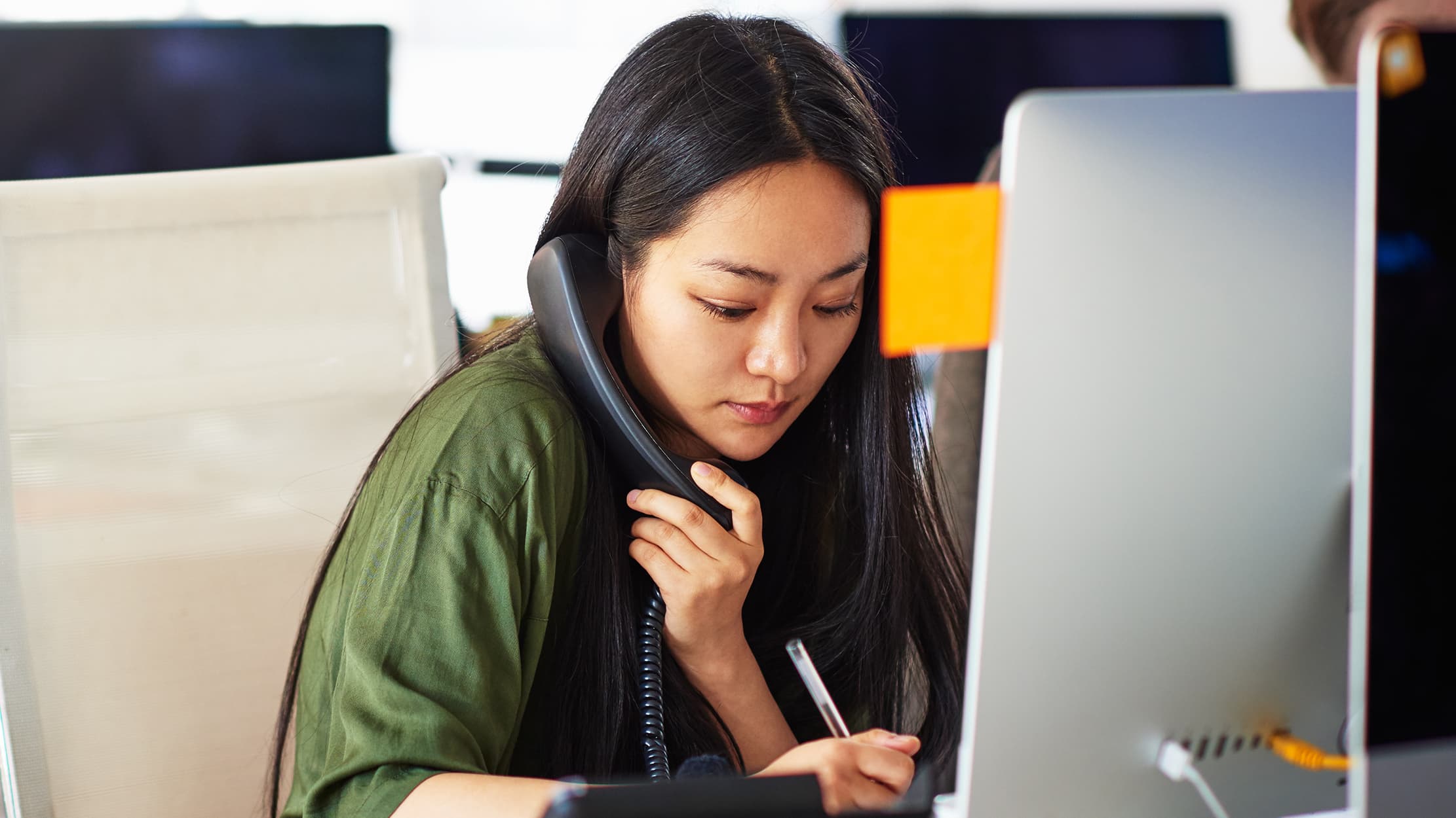 Une gérante prend le temps de téléphoner pendant qu'elle travaille sur son ordinateur portable.