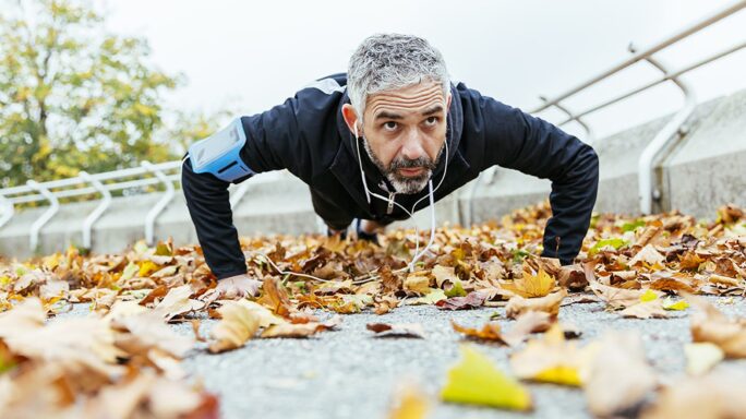 Un homme en faisant des pompes, entouré de feuilles d'automne