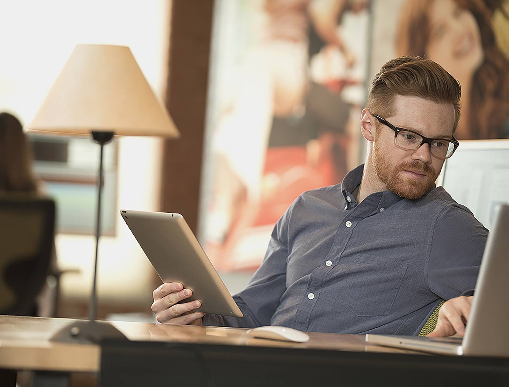 Een man werkt met zijn laptop en tablet en laat heel zijn kantoor papierloos werken.