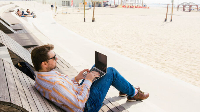 Een man is op vakantie aan het werk op zijn laptop, om als accountant altijd beschikbaar te zijn