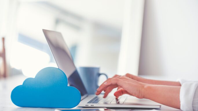 Iemand werkt op een laptop met een cloud-symbool ervoor, om te tonen dat ze in de cloud werken als kleine onderneming