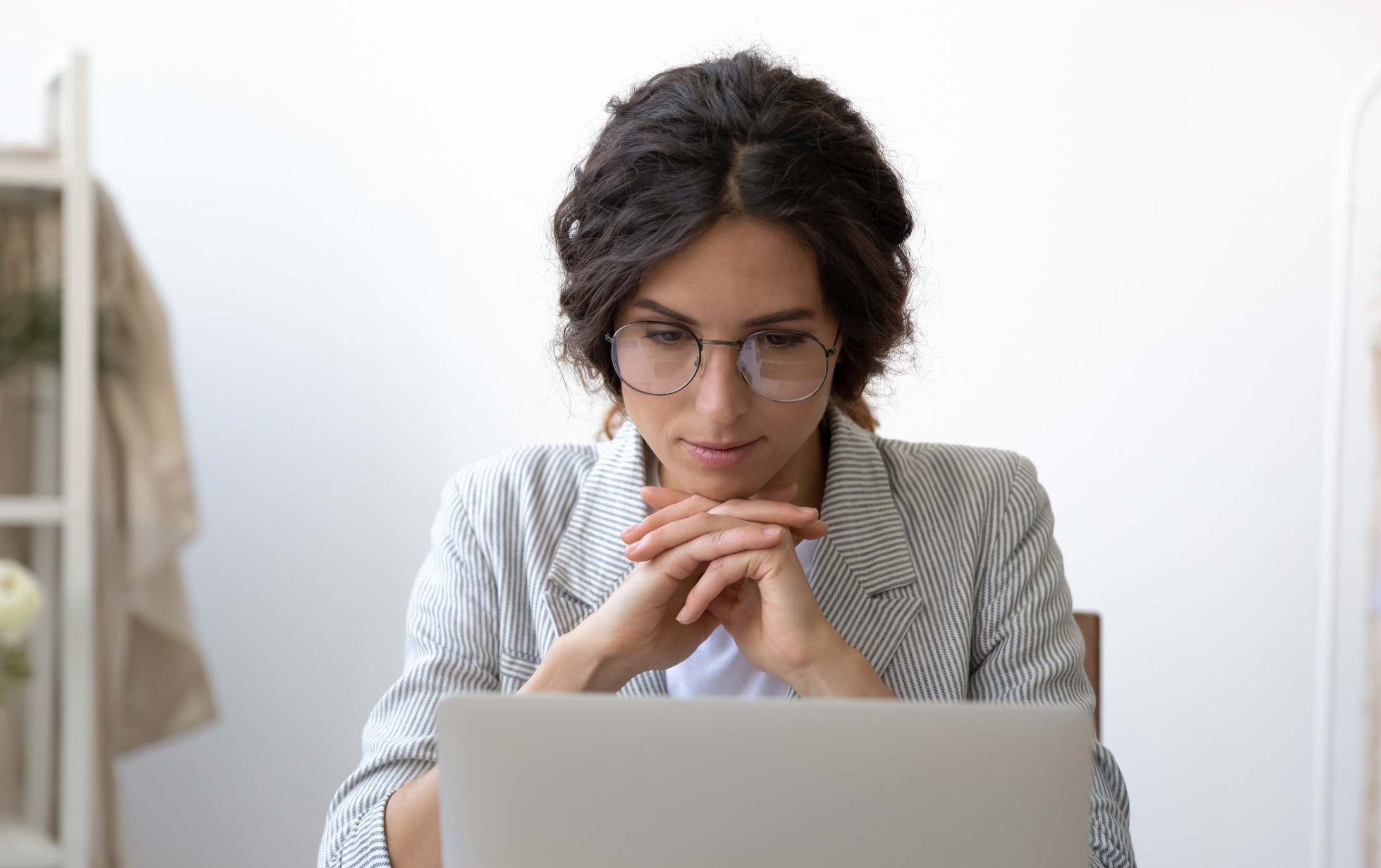 Een vrouw leest iets op haar laptop en denkt na over hoe ze een accountant zal kiezen voor haar kleine onderneming.
