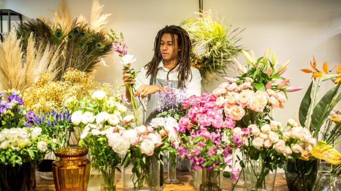 Een man herschikt de planten in zijn bloemenwinkel, een kleine onderneming