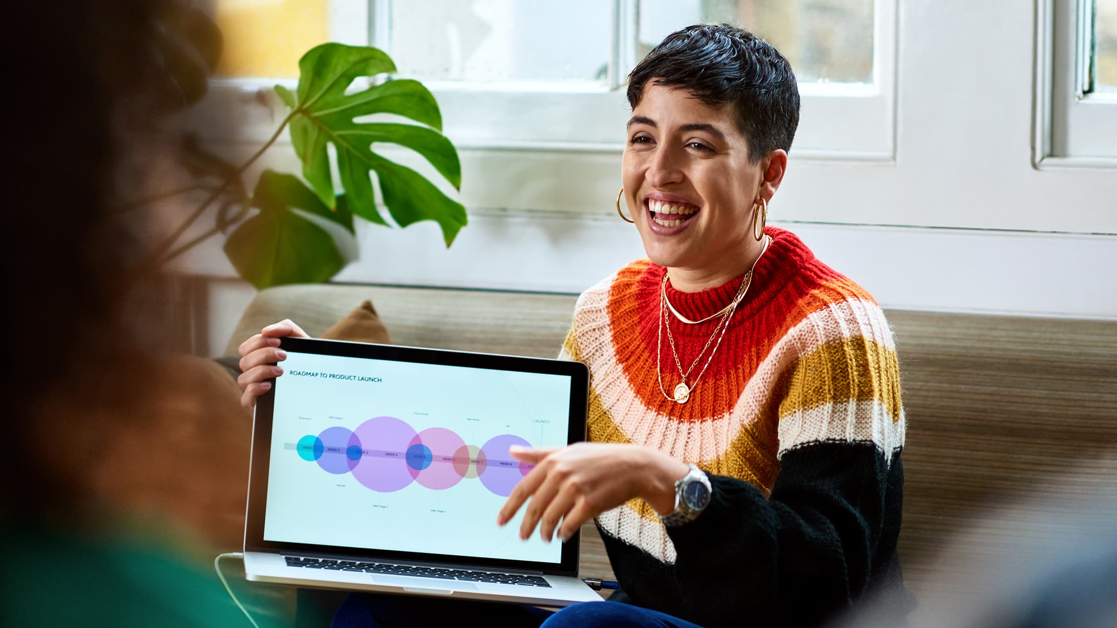 Een vrouw toont een nieuwe technologie met grafieken op haar laptop aan haar collega's