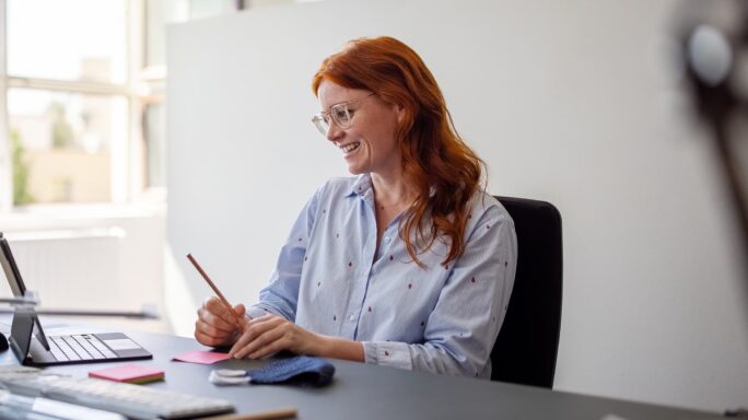 Een accountant kijkt lachend naar haar computerscherm en is blij dat ze voor nichemarkten werkt.