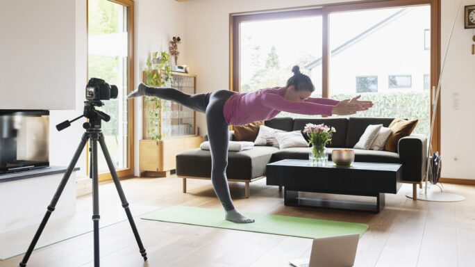 Een vrouw is haar online yogales aan het filmen voor haar financieel fit sportbedrijf.