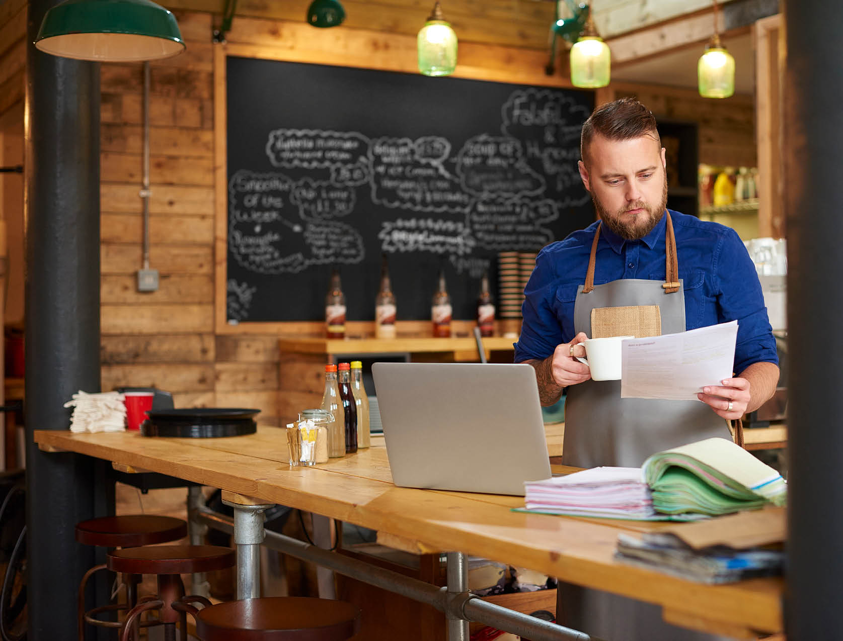 Empreendedor em restaurante com computador e papéis